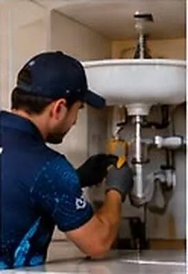 Plumber fixing pipework under a basin